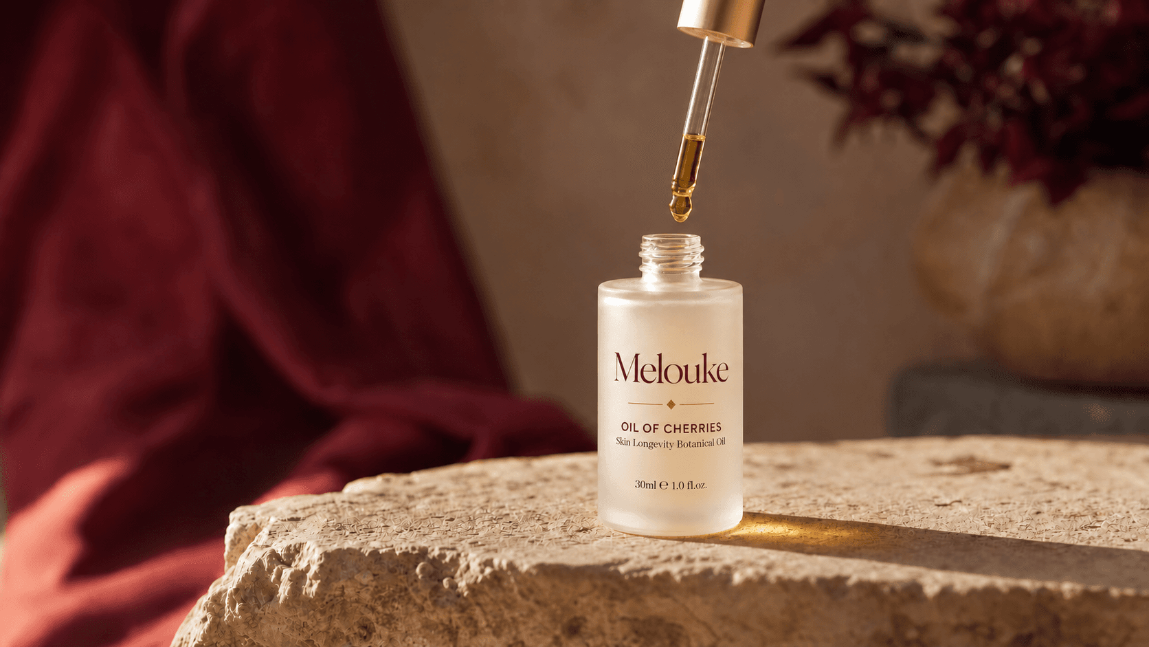 Flacon d’huile de soin de la peau aux noyaux de cerises Maison Melouke posé sur une pierre calcaire de l’Atlas avec pipette dorée